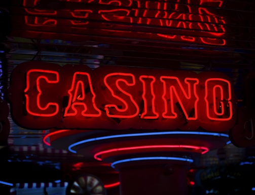 Neon lights display the word 'CASINO' in bright red, standing out against a dark background. The vibrant glow reflects a lively and bustling atmosphere.